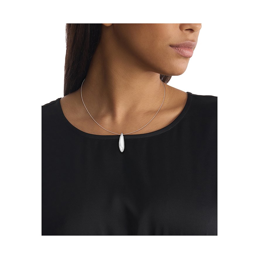 Close-up: Calvin Klein druppelhalsketting van roestvrij staal, gedragen door model voor een zwarte top.