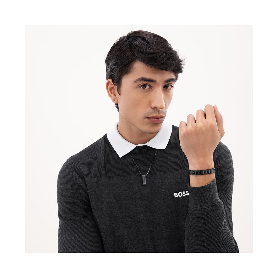 Een man draagt een Boss roestvrijstalen ketting met een verticaal, zwart element en een bijpassende armband.