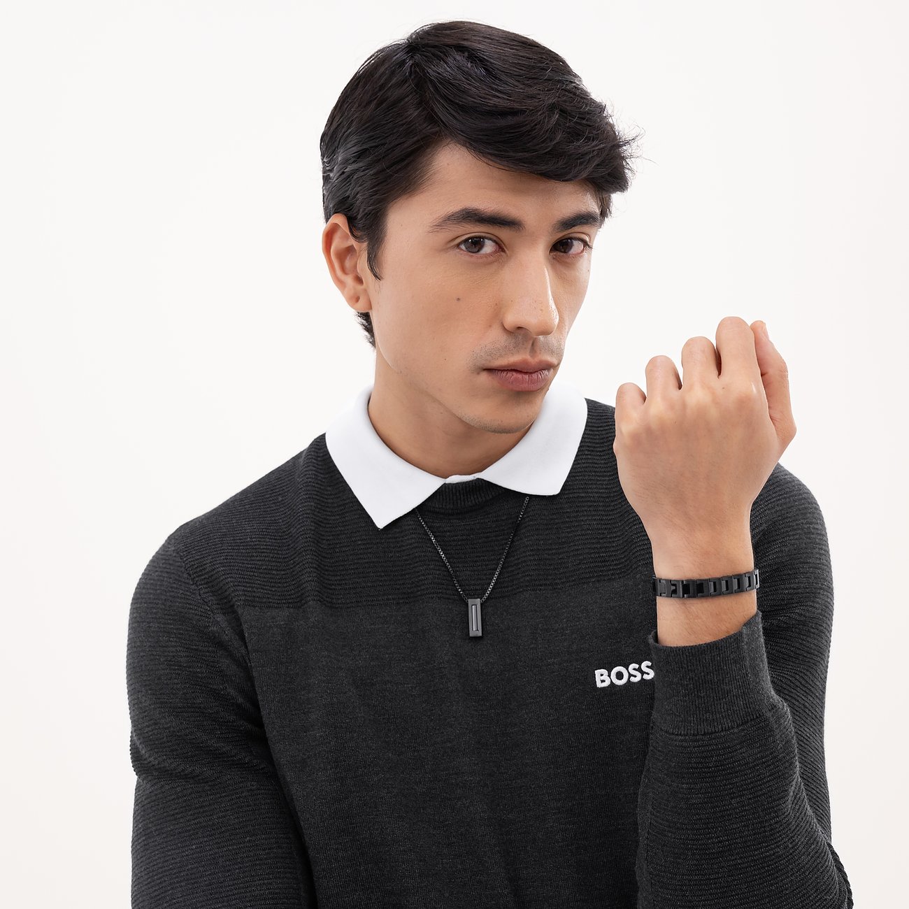 Een man draagt een Boss roestvrijstalen ketting met een verticaal, zwart element en een bijpassende armband.