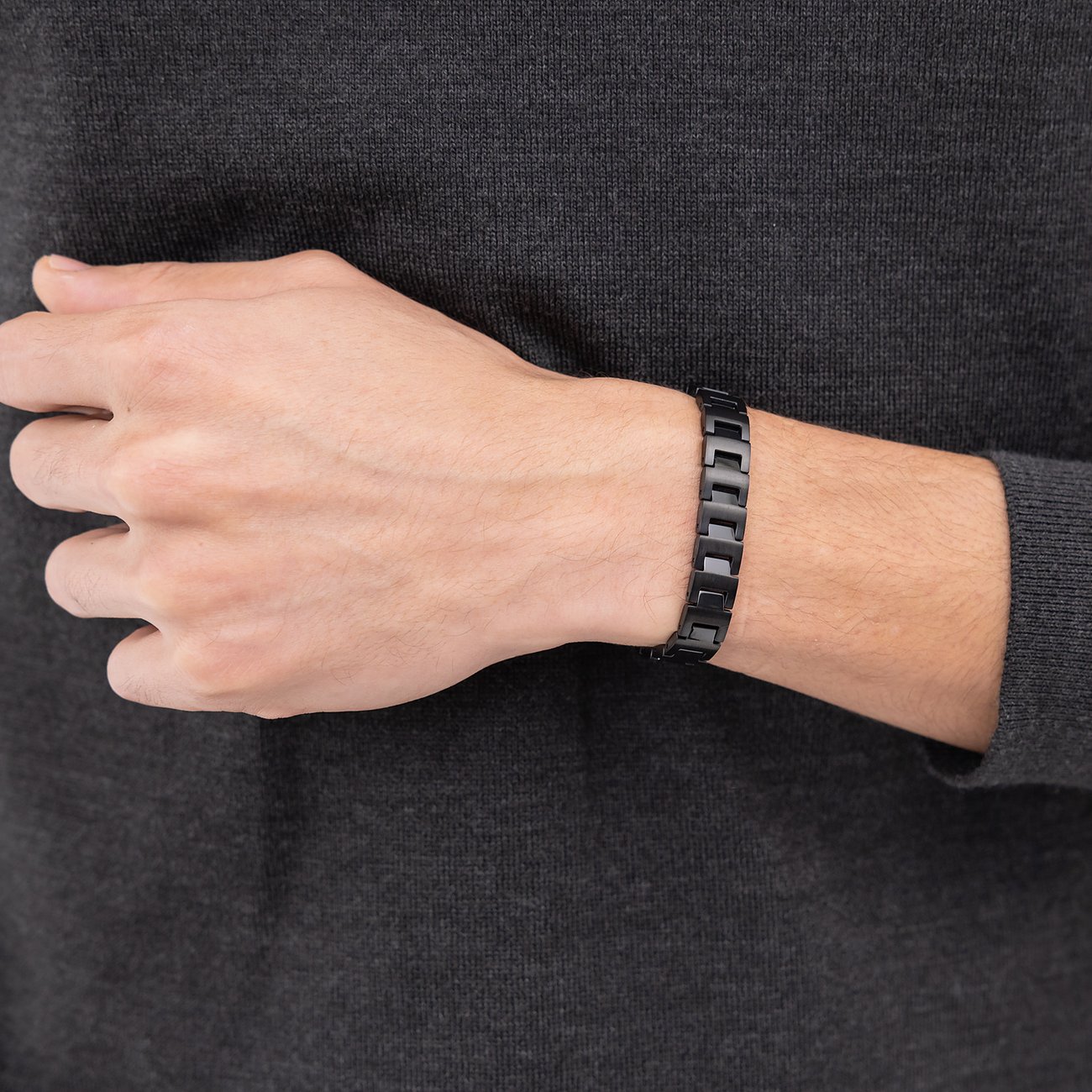 Am Handgelenk eines Mannes sitzt ein Boss-Armband aus schwarzem Edelstahl mit glatten Gliedern.