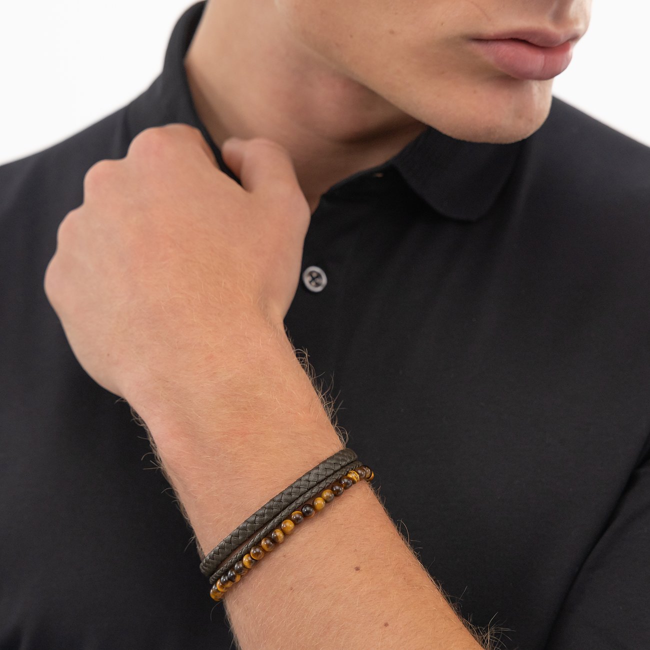 Een Boss armbanden set van meerdere lederen en kralen armbanden om de pols van een man.
