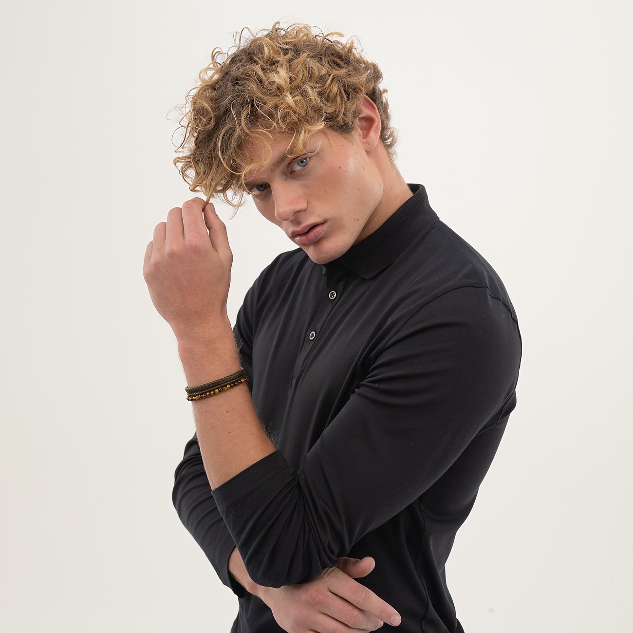 Een paspop draagt een Boss leren armband en siert zich met twee armbanden met parels.