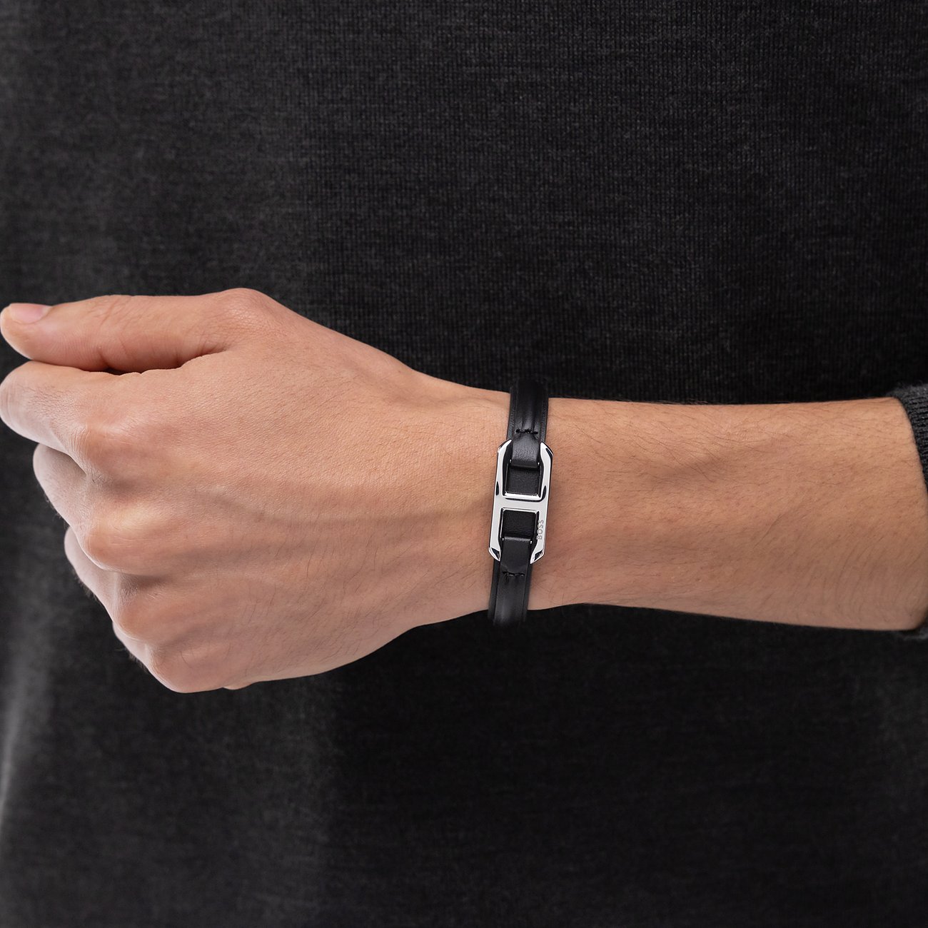 Am Handgelenk getragenes Boss Leder Armschmuck Armband in Schwarz mit silberfarbener Metallschnalle.