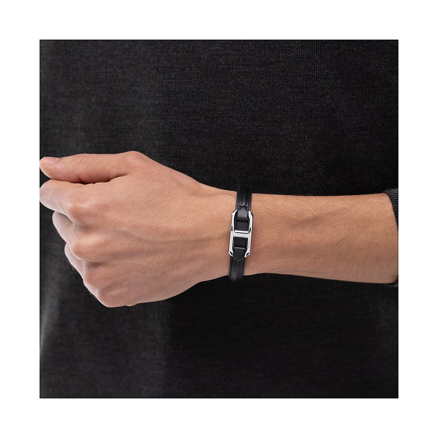 Ein Boss Armschmuck aus schwarzem Leder mit einem zentralen silberfarbenen Metallelement am Handgelenk eines Mannes.
