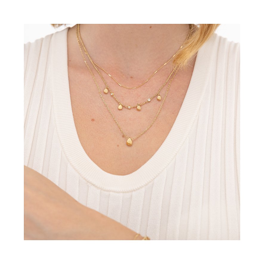 Drei goldene Boss-Halsketten aus Edelstahl am Hals einer Frau. Eine Kette mit tropfenförmigem Anhänger.