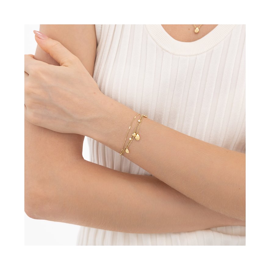 Ein goldenes Boss-Armband aus Edelstahl mit mehreren Ketten und kleinen blattförmigen Anhängern, am Handgelenk getragen.