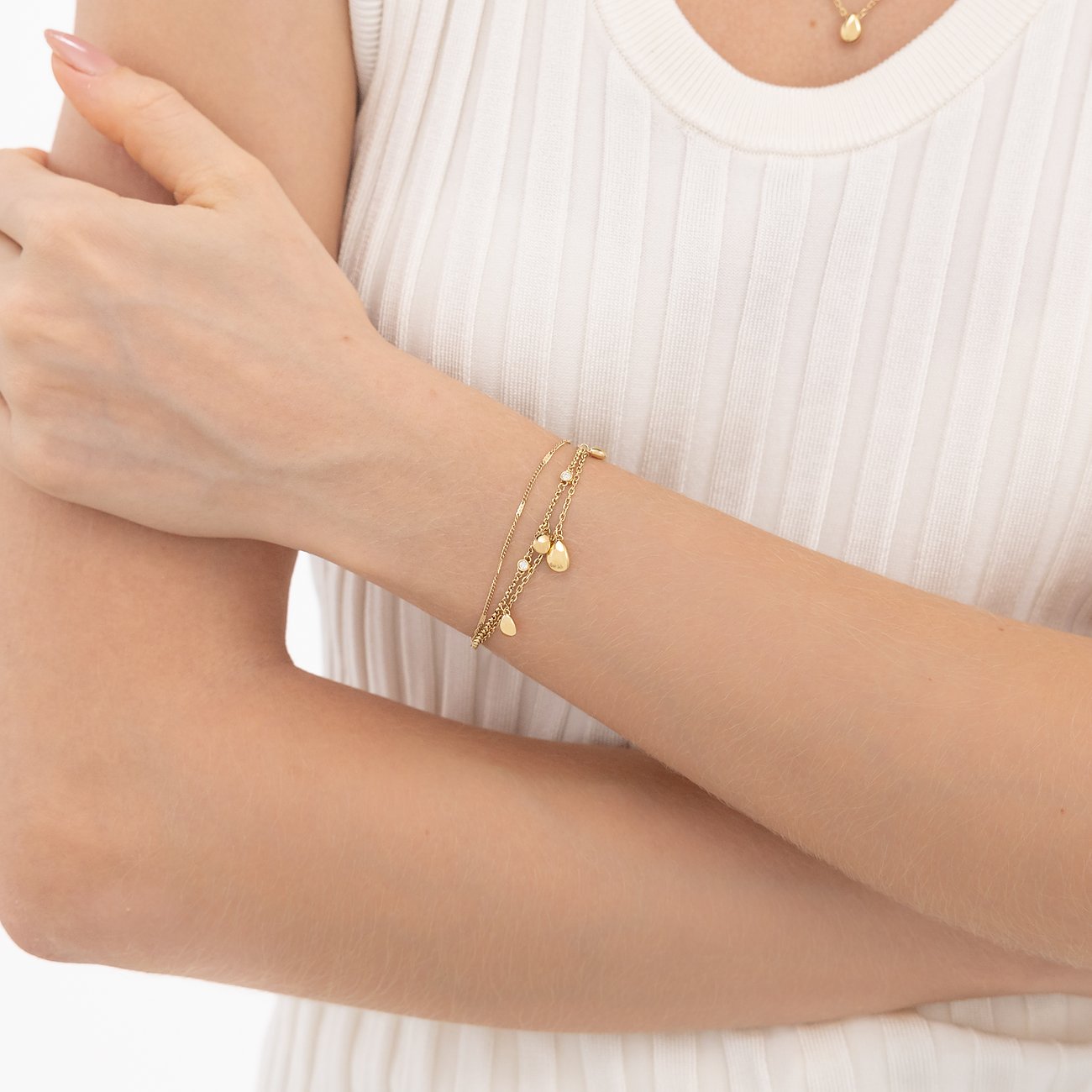 Ein goldenes Boss-Armband aus Edelstahl mit mehreren Ketten und kleinen blattförmigen Anhängern, am Handgelenk getragen.
