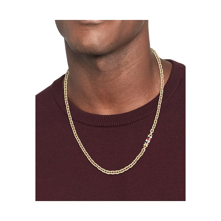 Tommy Hilfiger Halskette aus goldfarbenem Edelstahl, getragen von einem Mann im dunkelroten Pullover.