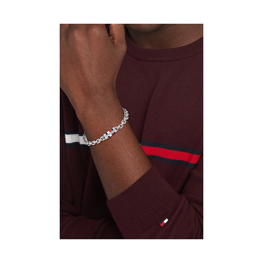 Zilveren Tommy Hilfiger roestvrijstalen armband met rood, wit en blauw logo om de pols van een man.