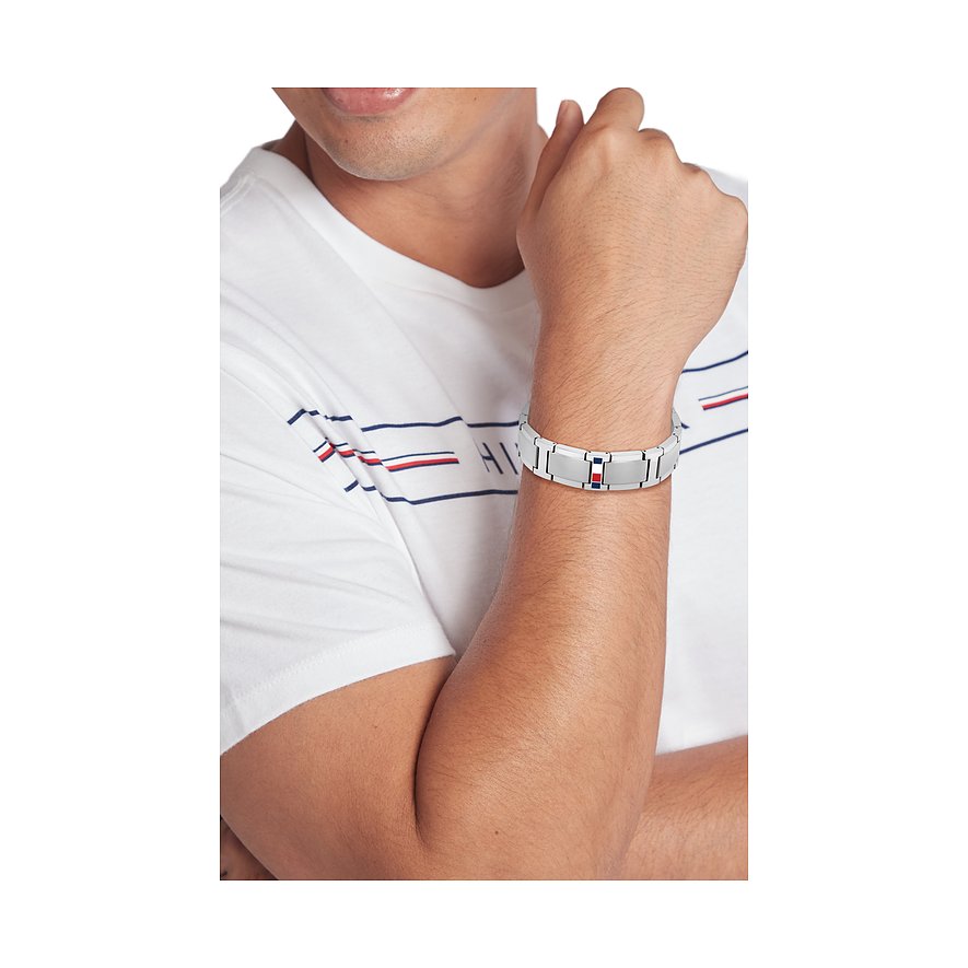 Ein Mann trägt die Tommy Hilfiger Herrenarmkette aus Edelstahl mit Tommy Hilfiger-Flaggen-Logo.