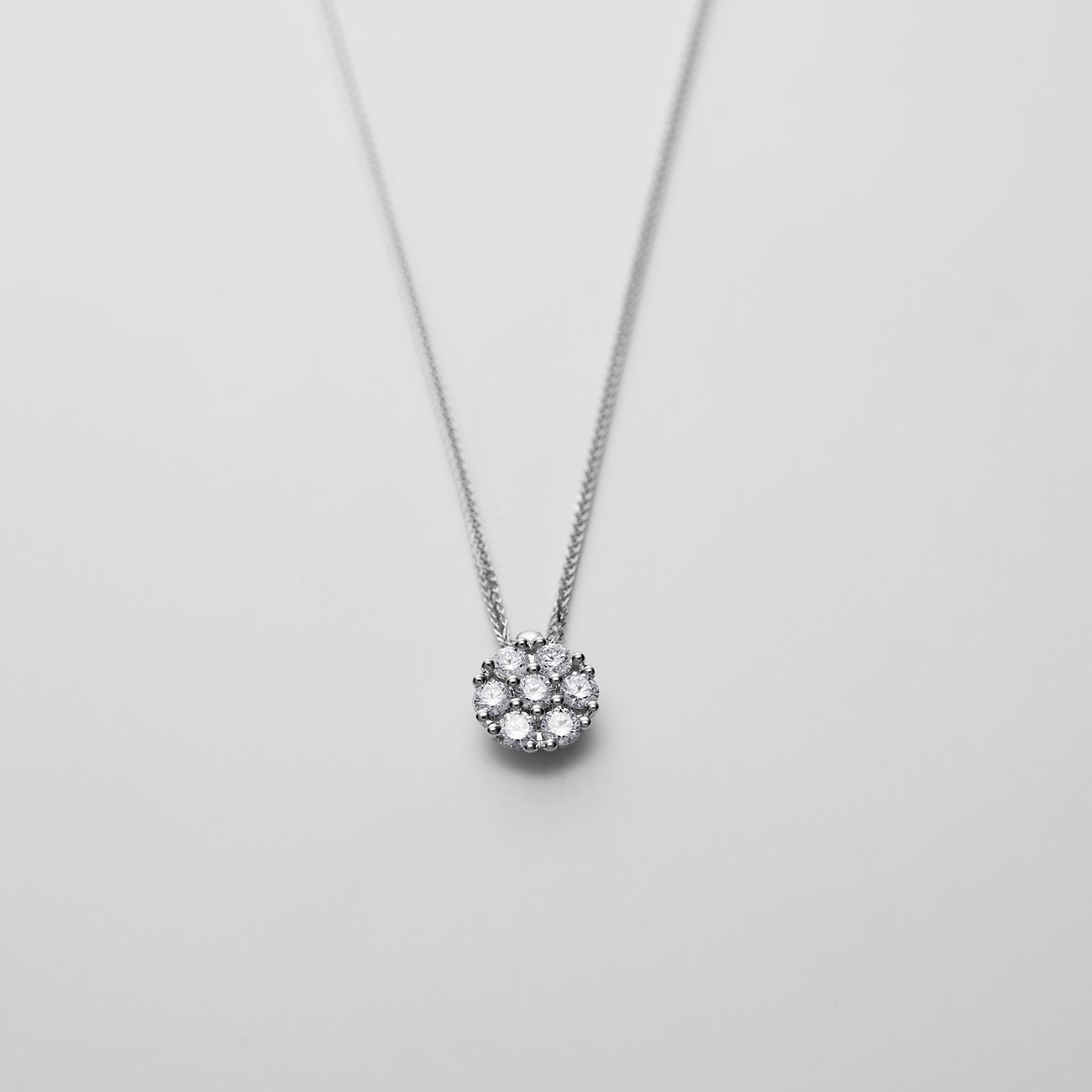 CHRIST Halsschmuck aus 585er Weißgold mit einem runden Anhänger, besetzt mit Diamanten in Blumenform.