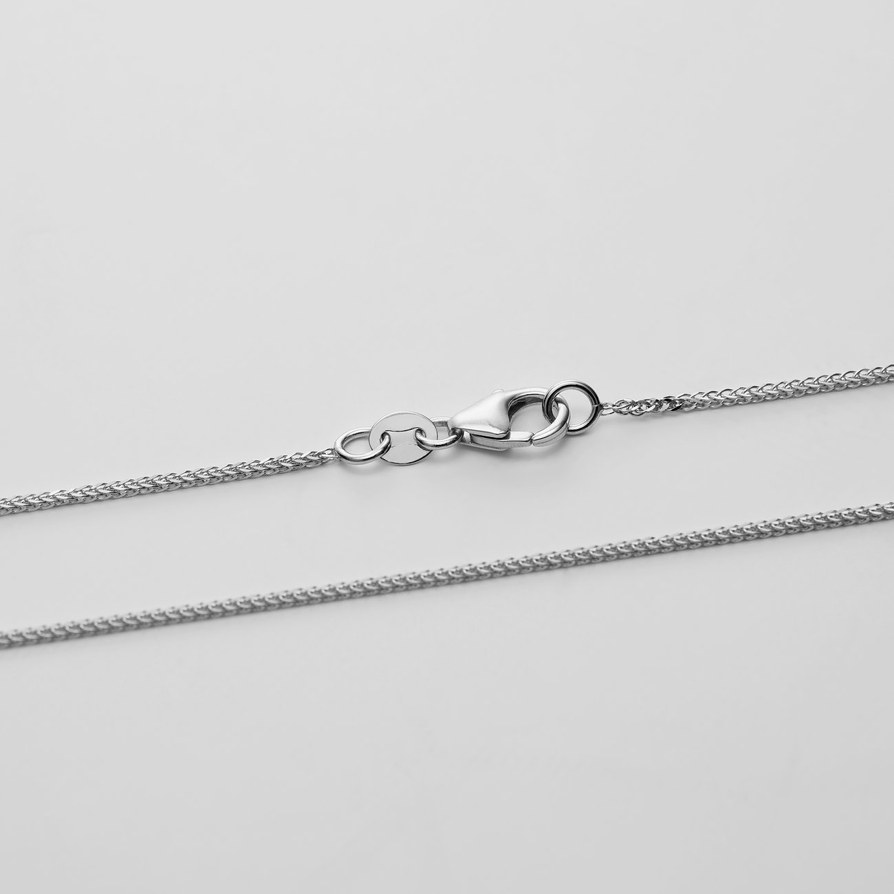 CHRIST Halskette aus 585er Weißgold, mittig ist der Karabinerverschluss der Ankerkette zu sehen.