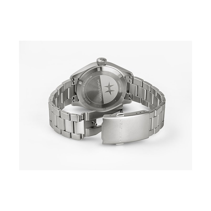 Rückseite einer Hamilton Herrenuhr aus satiniertem Edelstahl mit Hamilton-Logo, Gliederarmband und Verschluss auf hellem Grund.