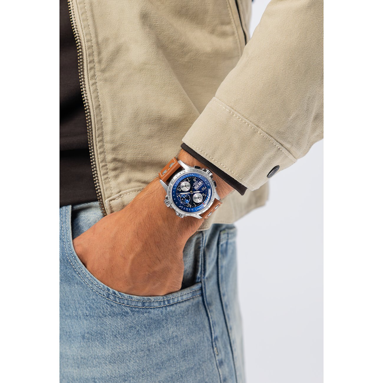 Am Handgelenk eines Mannes Hamilton Herrenuhr aus blauem Edelstahl mit braunem Lederband, Hand in Hosentasche.