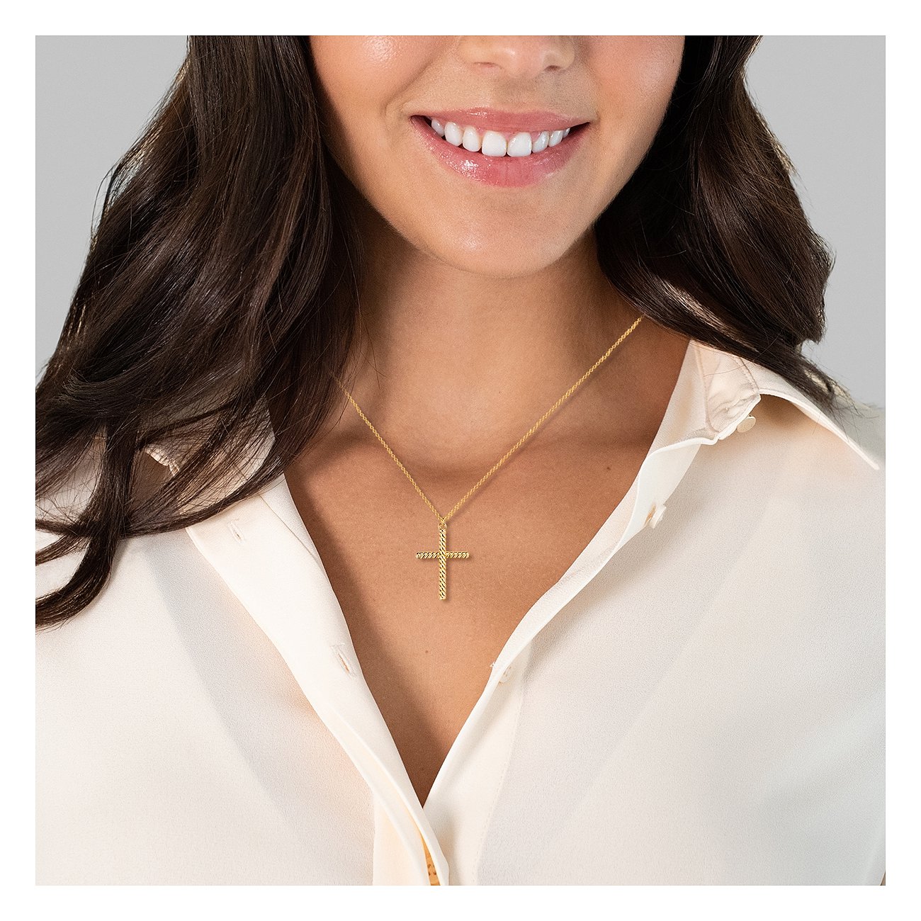 Une femme porte un collier doré Glanzstücke München avec une fine croix en argent massif 925.