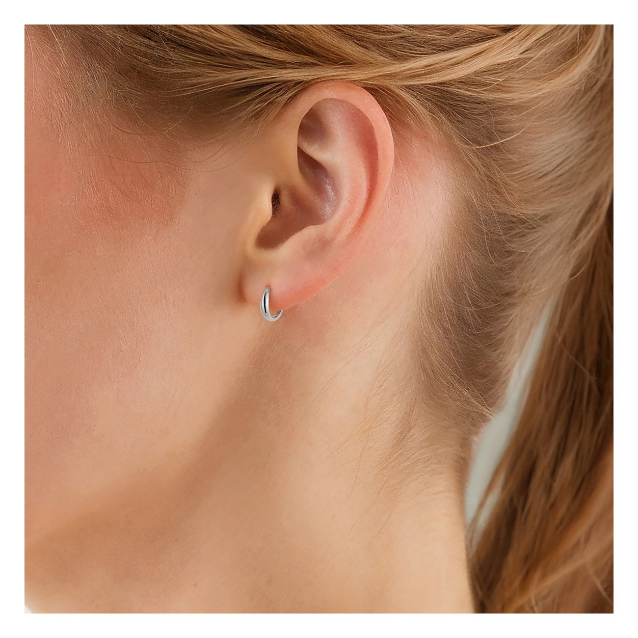 Un petit piercing d'oreille en argent de Glanzstücke München, en argent 925, est visible à l'oreille d'une personne.