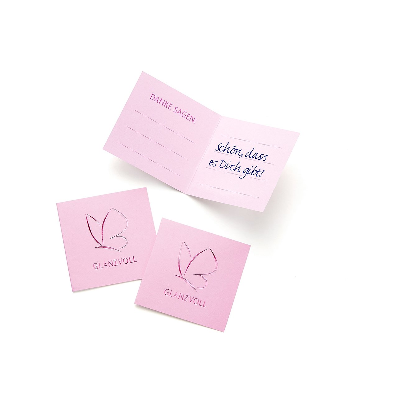 Drei rosa Glanzstücke München Kärtchen auf weißer Oberfläche. Zwei quadratisch mit Schmetterlingslogo „GLANZVOLL“. Eines aufgeklappt mit „DANKE SAGEN: Schön, dass es Dich gibt!“.