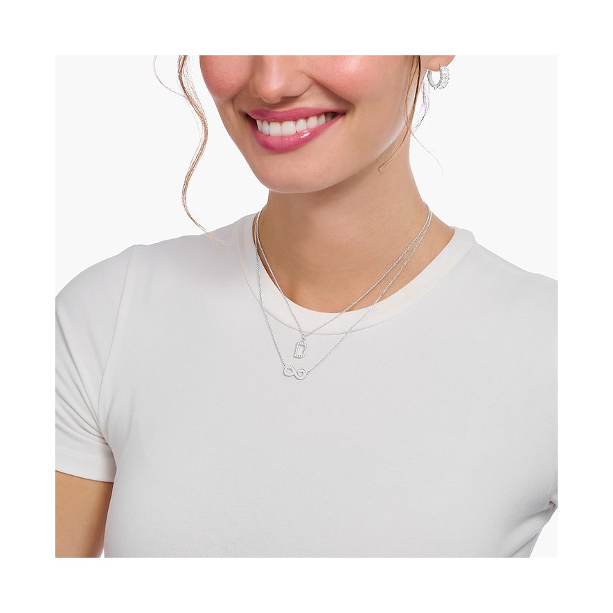 Eine Nahaufnahme einer Frau, die zwei Thomas Sabo Halsketten aus 925er Silber mit Zirkonia-Steinen trägt.