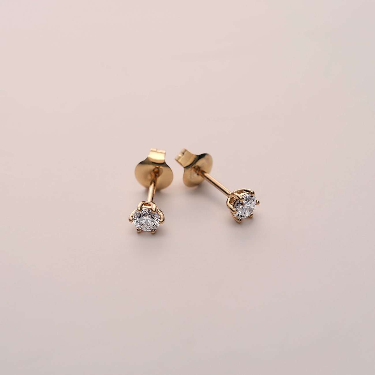 Ein Paar CHRIST Ohrstecker aus 585 Gelbgold mit funkelnden Diamanten, schräg liegend auf hellem Grund.