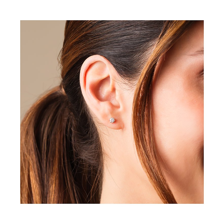 CHRIST Gelbgold-Ohrring mit Diamant am Ohr einer Frau mit braunen Haaren. Sie trägt nur einen Ohrstecker links.