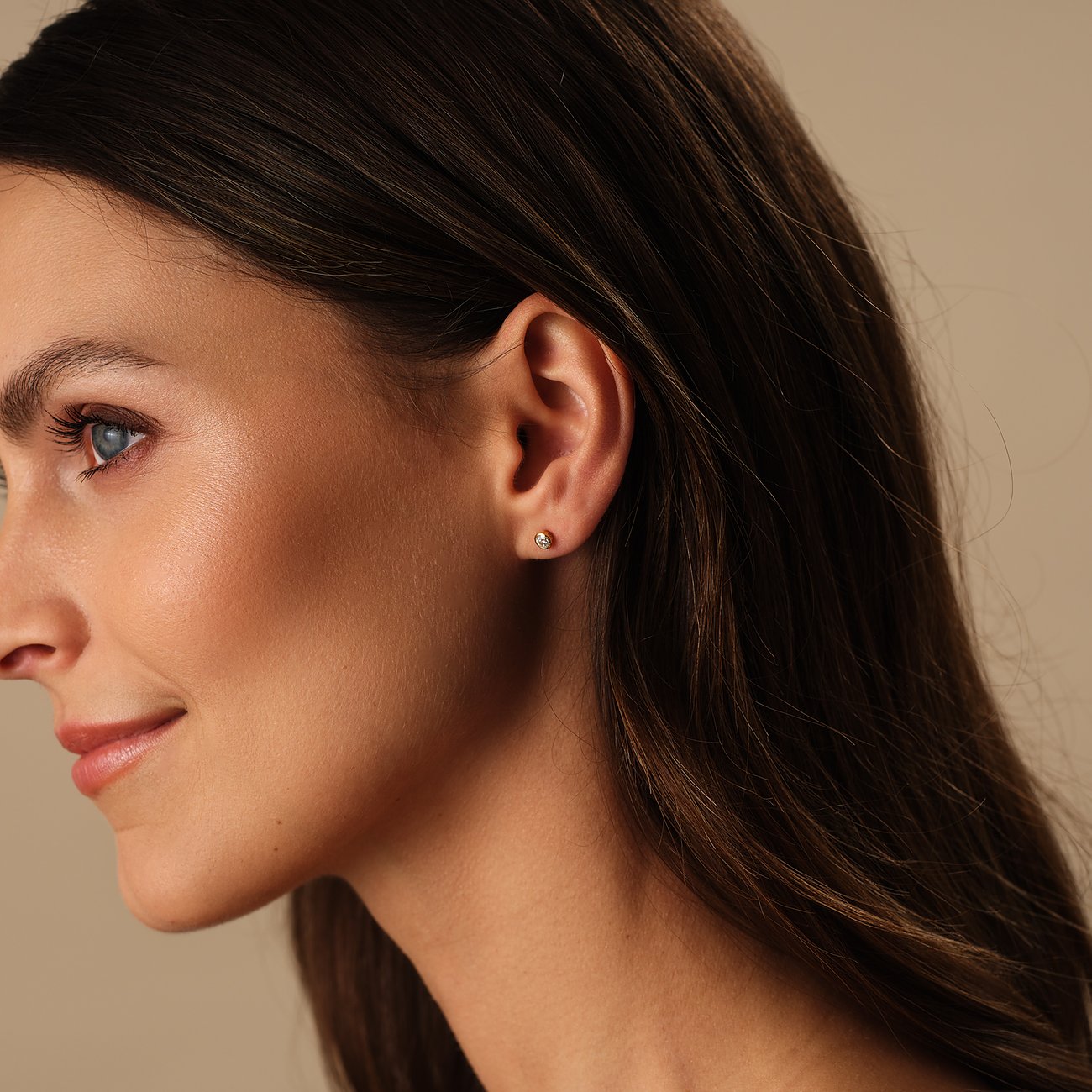 Nahaufnahme einer Frau im Profil, die einen einzelnen runden CHRIST Weißgold-Ohrstecker mit Diamant trägt.