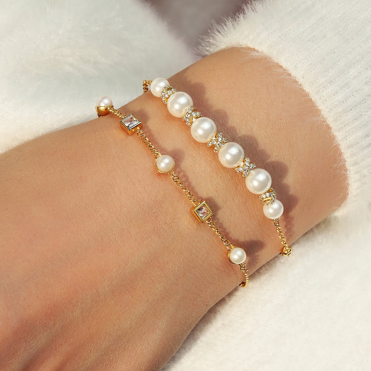 Ania Haie Armschmuck aus vergoldetem Silber mit weißen Perlen und Zirkonia in einer Nahaufnahme an einem Handgelenk.