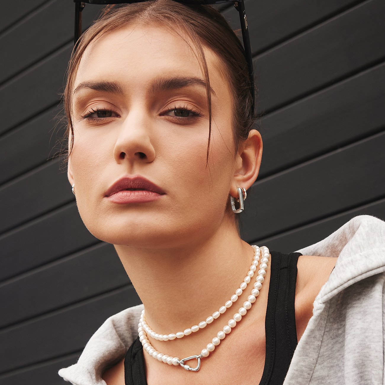 Modellen bär Ania Haie örhängen i 925 sterlingsilver med fyrkantig design, tillsammans med ett flerradigt pärlhalsband.