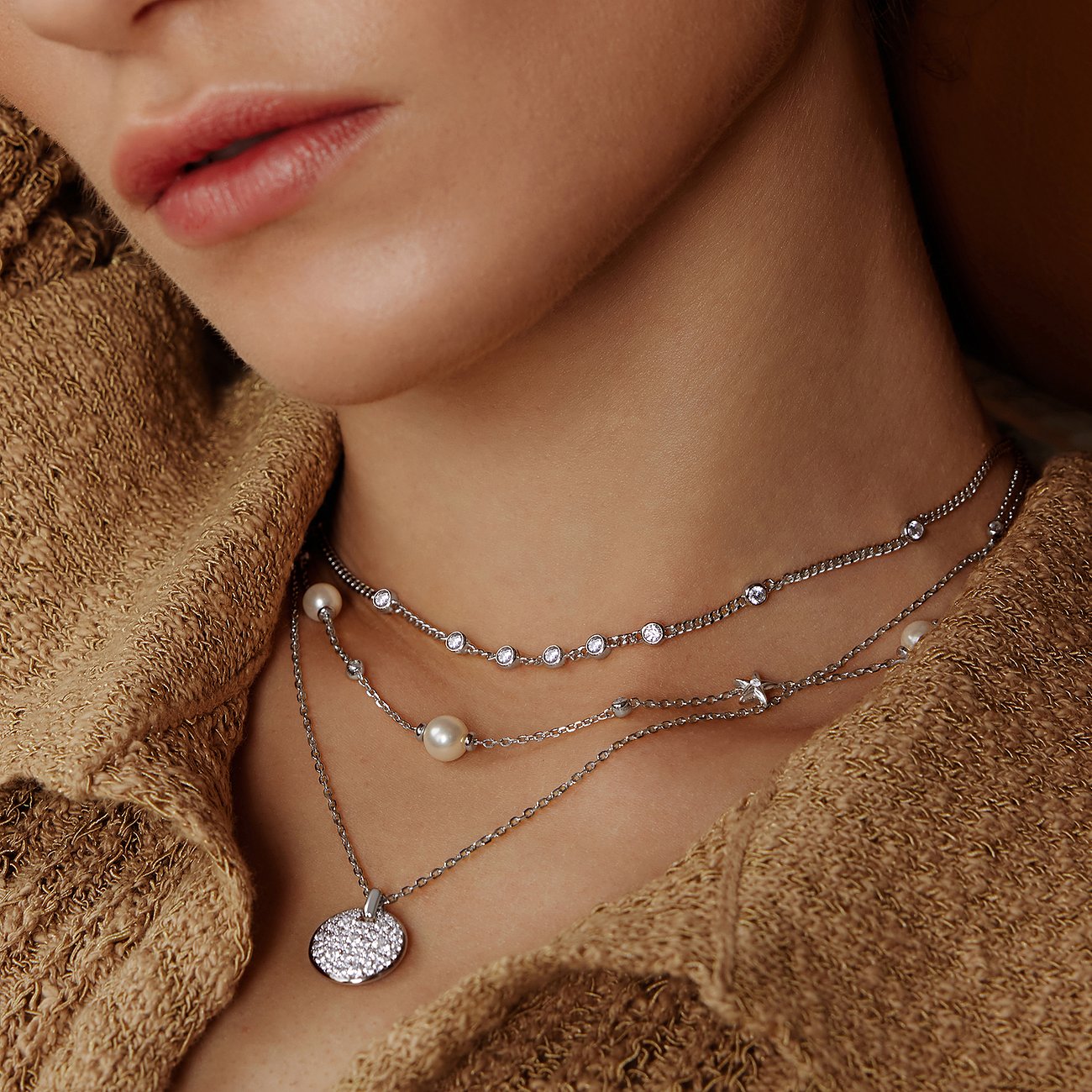 Close-up van vrouw met een drielaags zilveren Ania Haie halsketting, versierd met zirkonia en parels.