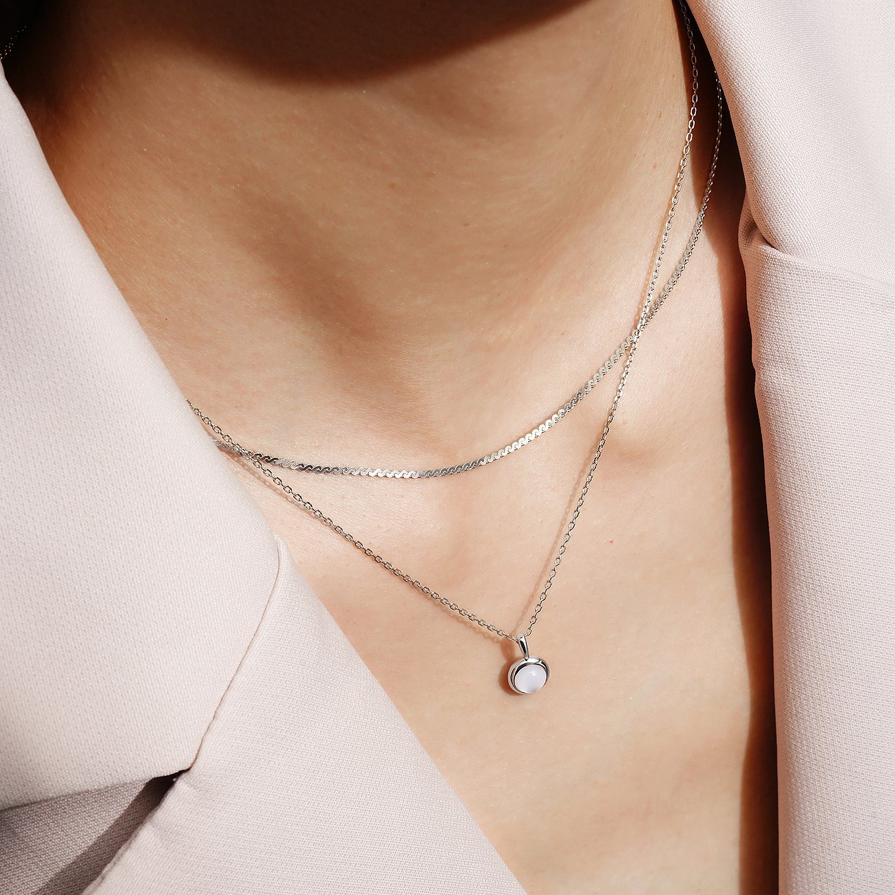 Ania Haie, zilveren dubbelrijige ketting met kleine zirkonia-hanger, gedragen op een lichte top.