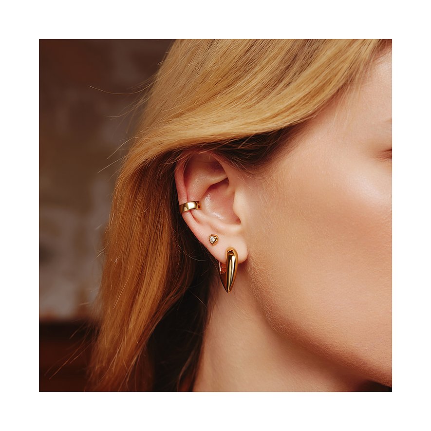 Gros plan d'une oreille avec trois bijoux d'oreille Ania Haie dorés : un ear cuff, un clou en zircone et une créole cœur.