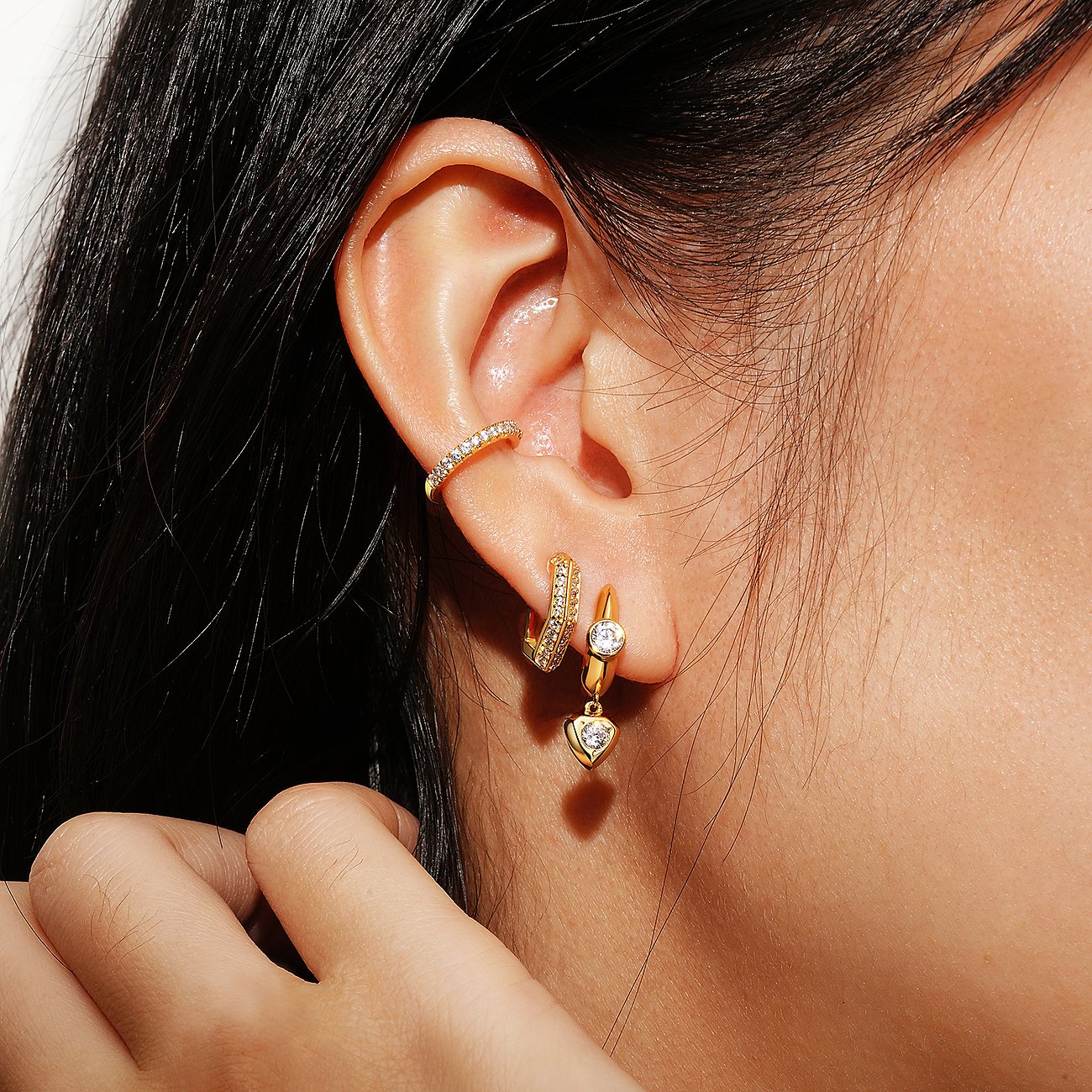Des boucles d'oreilles Ania Haie en argent plaqué or avec zircone sont portées par une personne aux cheveux foncés.