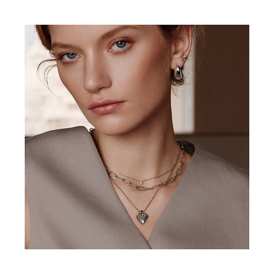 Le mannequin porte un collier Ania Haie superposé en argent 925 à plusieurs rangs, pendentif cœur et pierres claires.