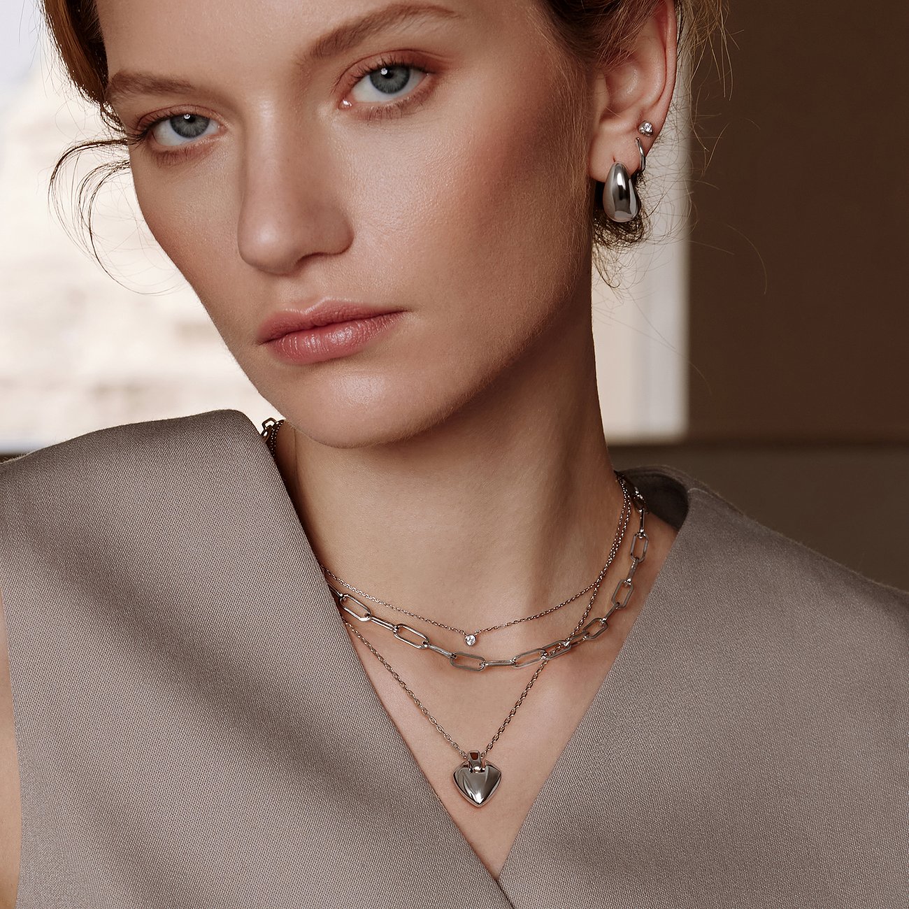 Le mannequin porte un collier Ania Haie superposé en argent 925 à plusieurs rangs, pendentif cœur et pierres claires.