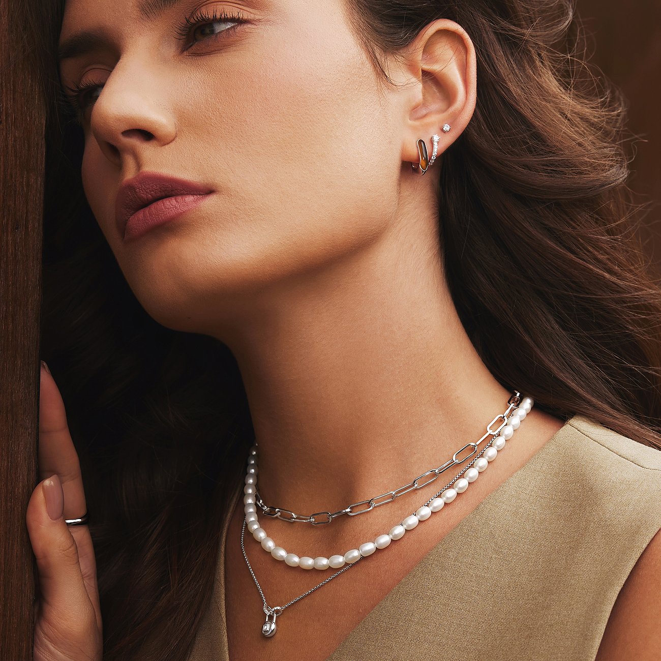 Close-up van vrouw met een Ania Haie zilveren multi-rijige halskettingset, inclusief een parelketting.