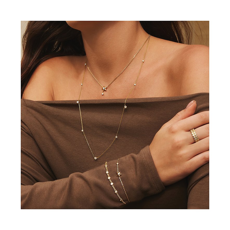 Model trägt zwei zarte goldene Ania Haie Halsketten mit kleinen Zirkonia-Steinen und eine passende Armkette.