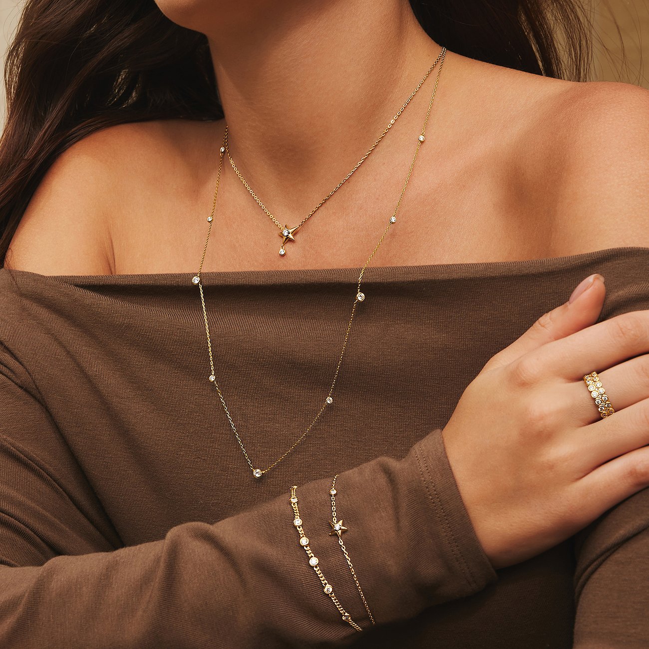 Model trägt zwei zarte goldene Ania Haie Halsketten mit kleinen Zirkonia-Steinen und eine passende Armkette.