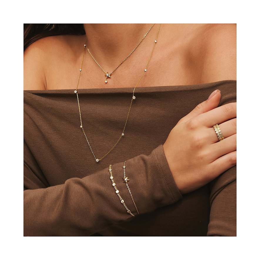 Le mannequin porte des bijoux de bras Ania Haie en argent plaqué or avec zircone, collier et bague assortis.