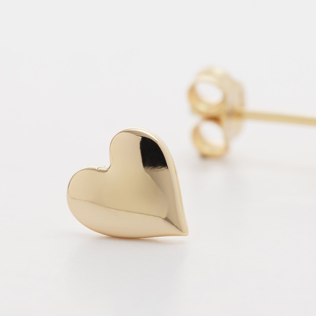 Ein FAVS glänzender goldener Herz-Ohrstecker aus 925er Silber mit leicht unebener Oberfläche zu sehen.