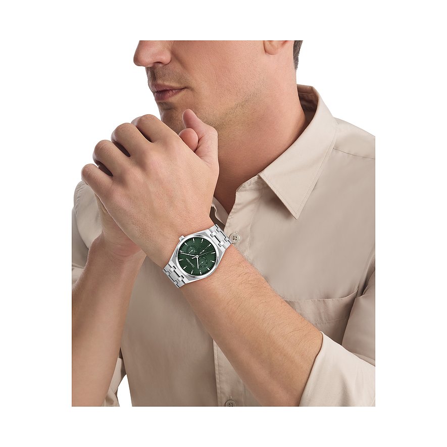 Calvin Klein Herrenuhr aus Edelstahl am Handgelenk eines Mannes, mit grünem Zifferblatt und drei Hilfszifferblättern.
