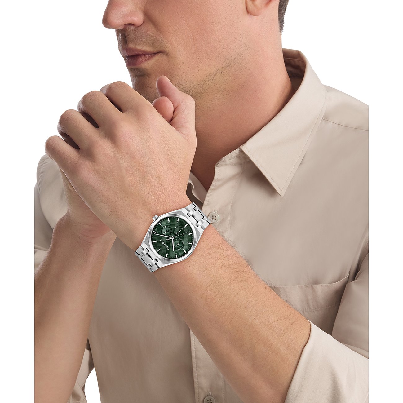 Calvin Klein Herrenuhr aus Edelstahl am Handgelenk eines Mannes, mit grünem Zifferblatt und drei Hilfszifferblättern.