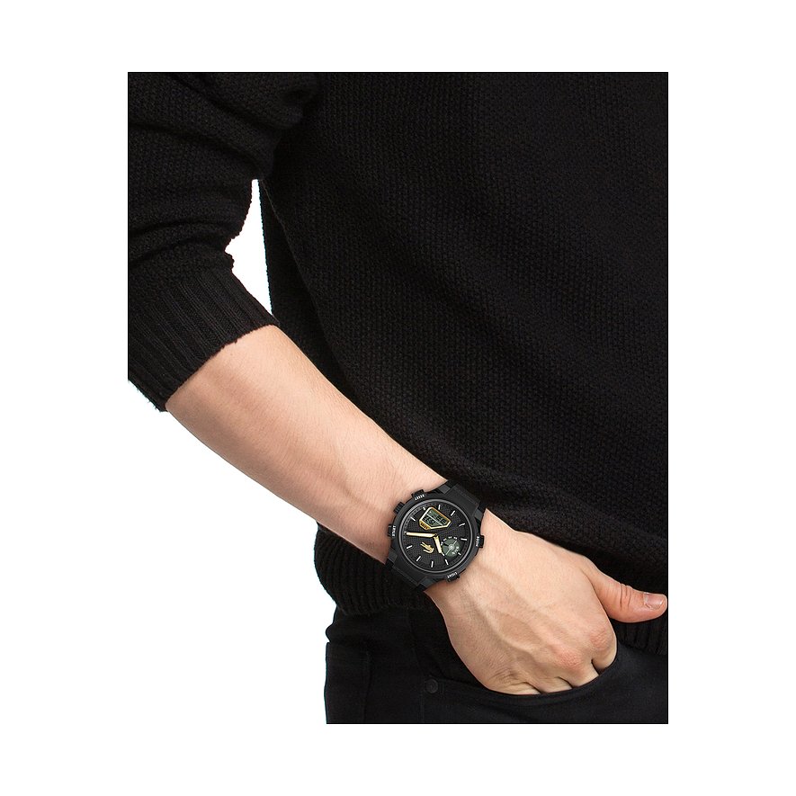 Am Handgelenk eines Mannes getragen: Eine schwarze Edelstahl-Herrenuhr von Lacoste mit digitaler Anzeige.