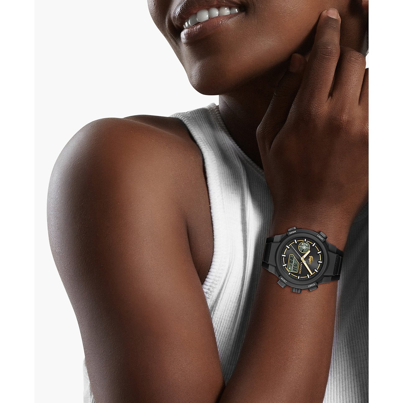 Eine Frau mit Lacoste Damenuhr aus schwarzem Edelstahl und Kunststoff am linken Handgelenk, teilweise verdeckt.