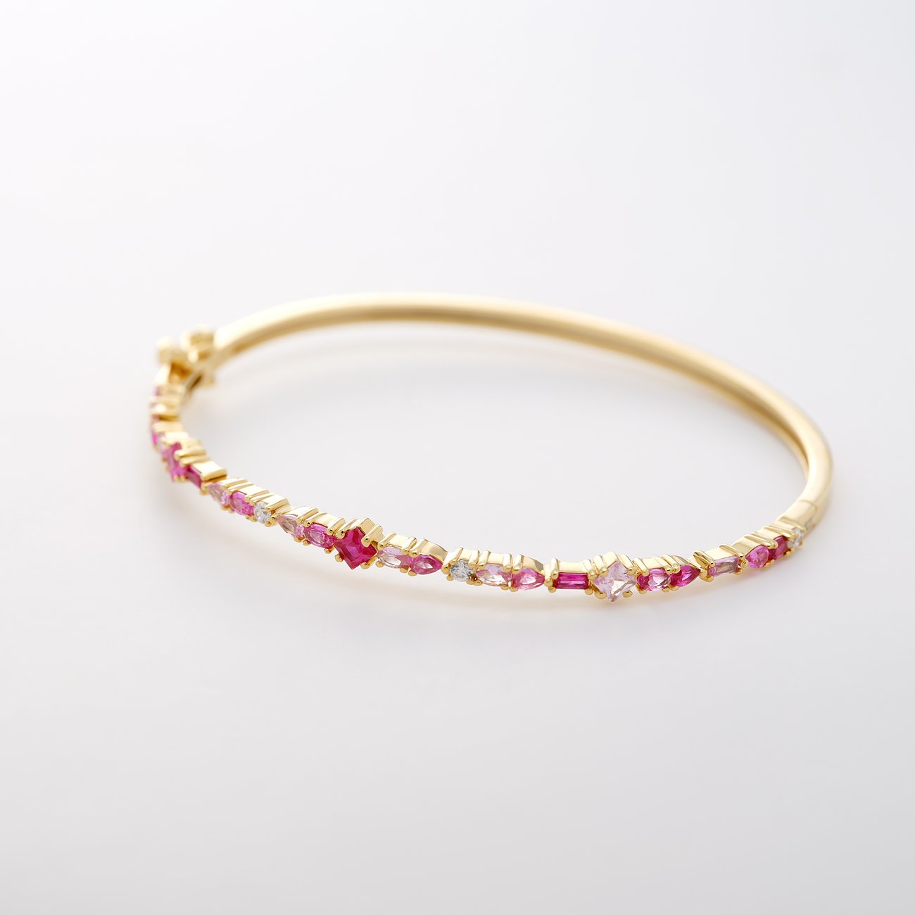 CHRIST Armreif mit recyceltem Gold, besetzt mit unregelmäßig angeordneten rosa Zirkonia-Farbsteinen.