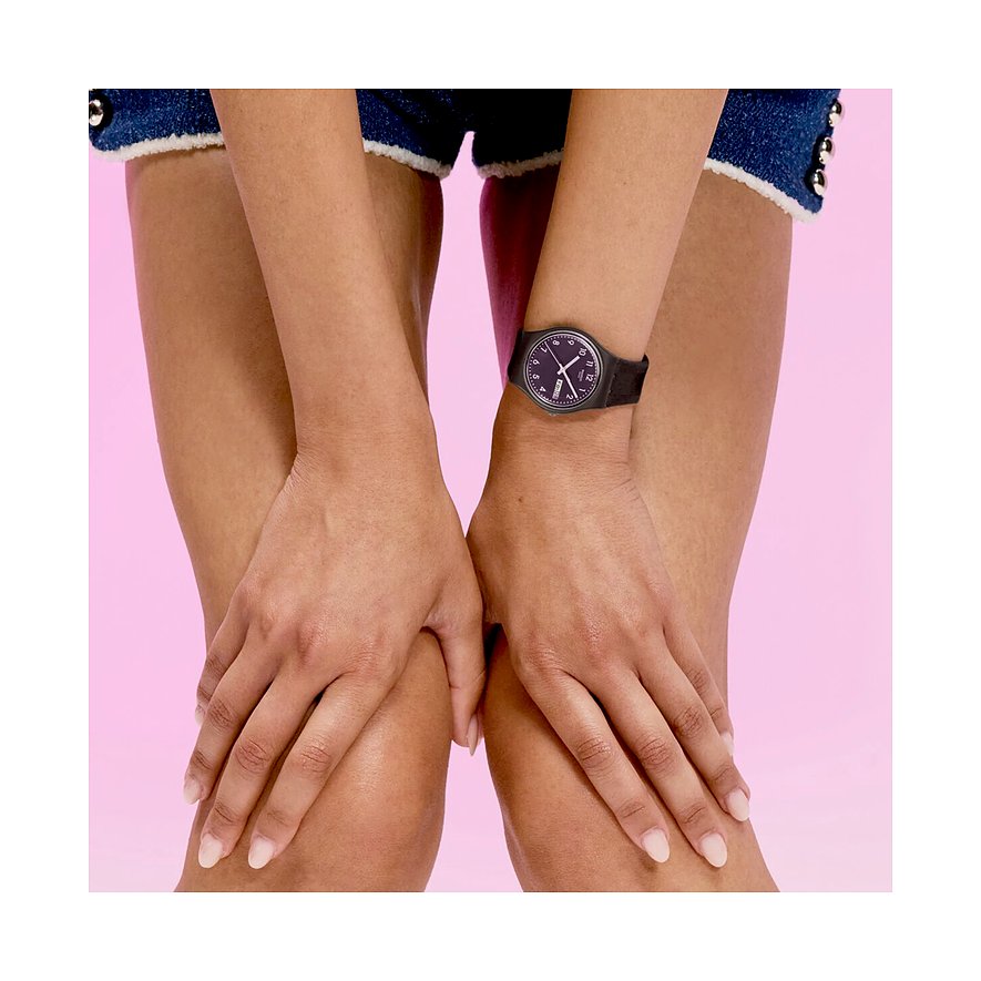 Am Handgelenk einer Person ist eine schwarze Swatch Unisexuhr aus Kunststoff mit schwarzem Zifferblatt zu sehen.