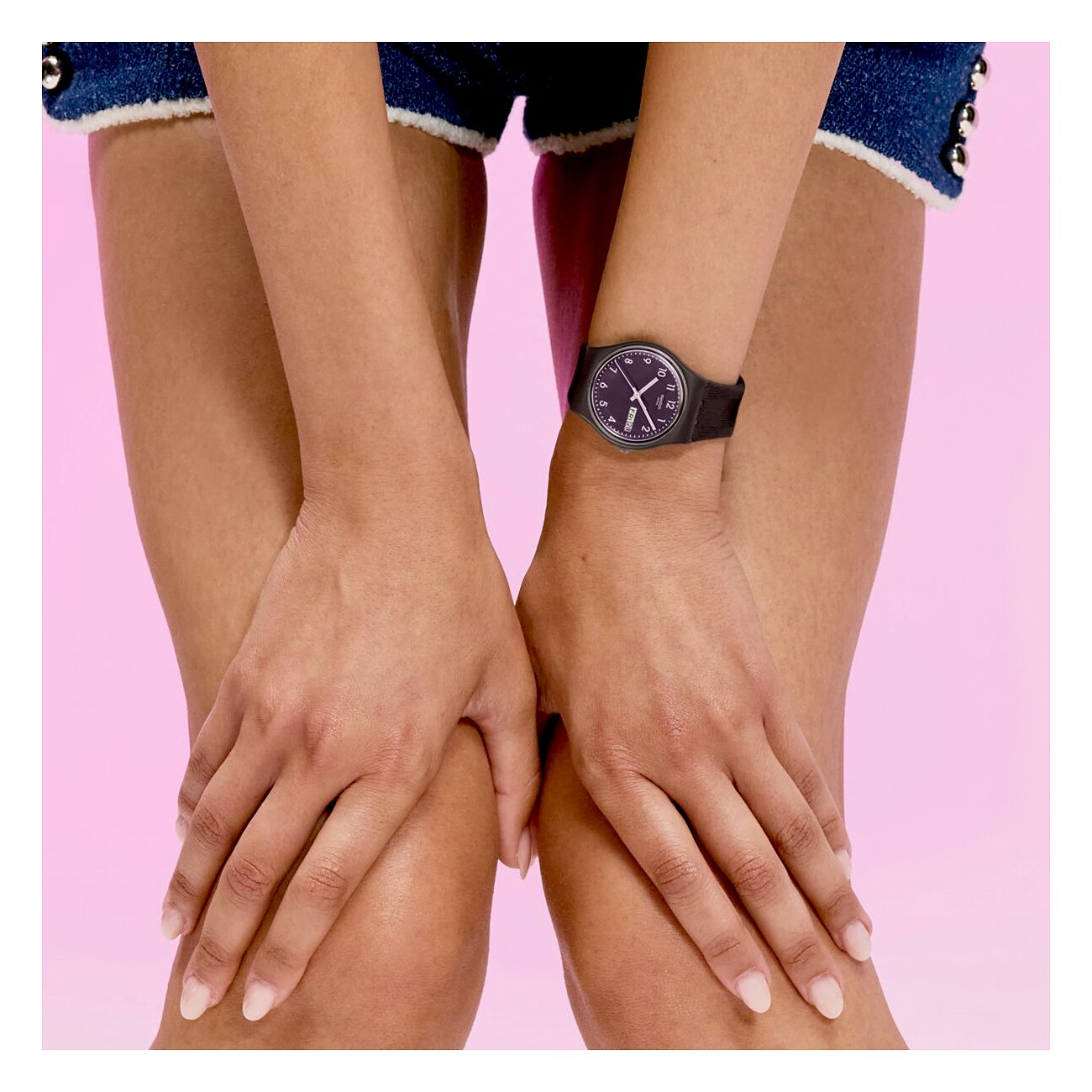 Am Handgelenk einer Person ist eine schwarze Swatch Unisexuhr aus Kunststoff mit schwarzem Zifferblatt zu sehen.