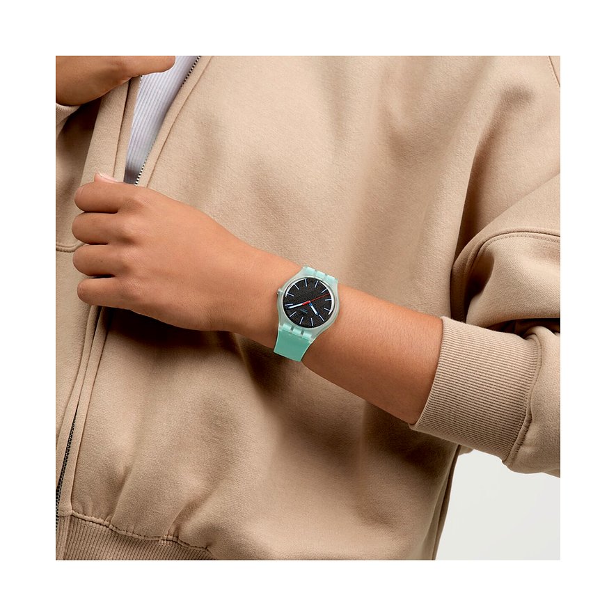 Eine Nahaufnahme zeigt eine Swatch Unisexuhr aus Kunststoff am Handgelenk mit grünem Armband und dunkelgrauem Zifferblatt.