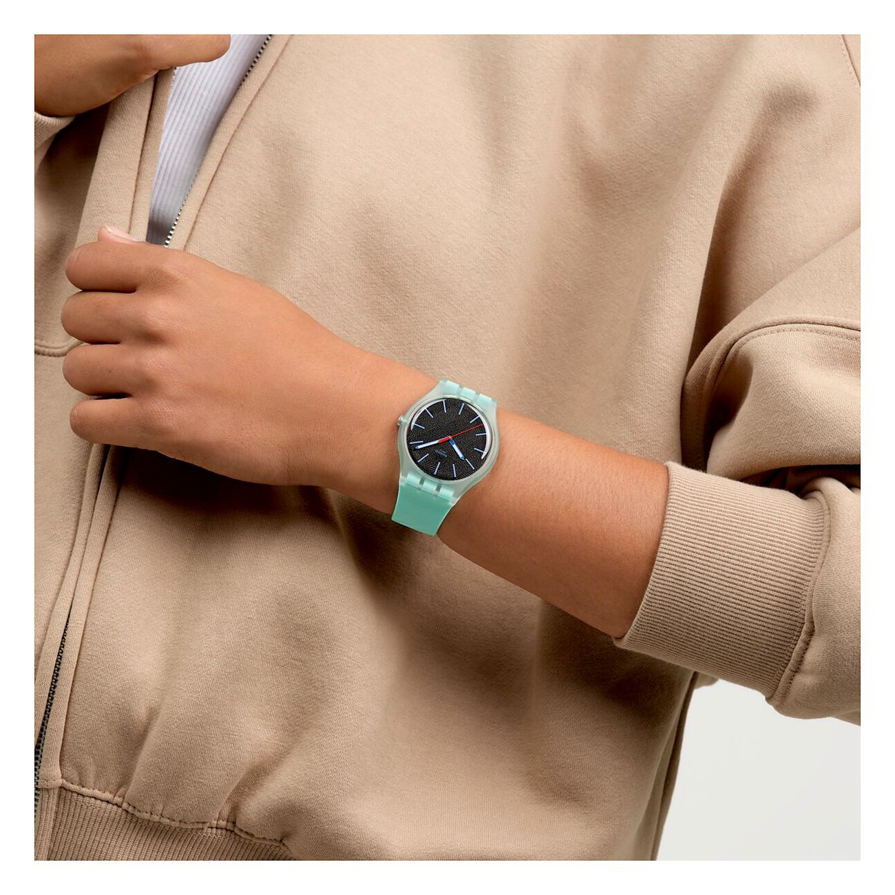 Eine Nahaufnahme zeigt eine Swatch Unisexuhr aus Kunststoff am Handgelenk mit grünem Armband und dunkelgrauem Zifferblatt.