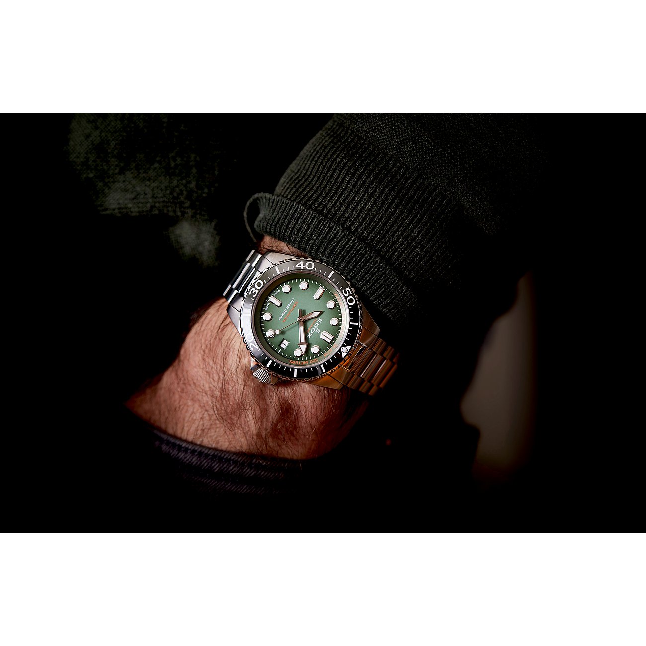 Am Handgelenk eines Mannes wird eine Edox Herrenuhr aus dunkelgrüner Keramik und Edelstahl getragen.