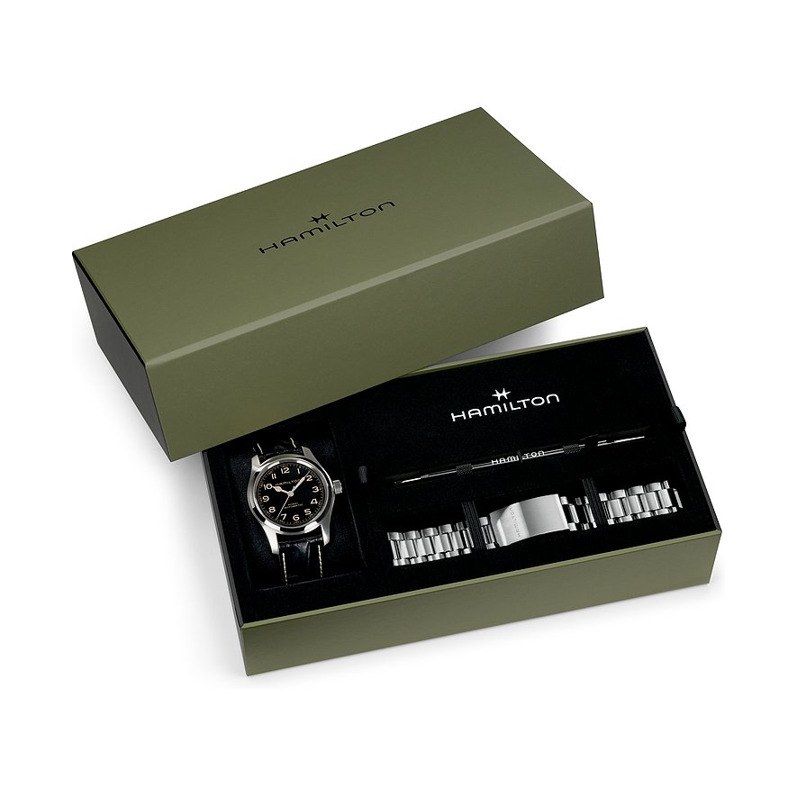 Die Hamilton Armbanduhr aus Edelstahl liegt in einer geöffneten, olivgrünen Box neben einem silbernen Wechselarmband.