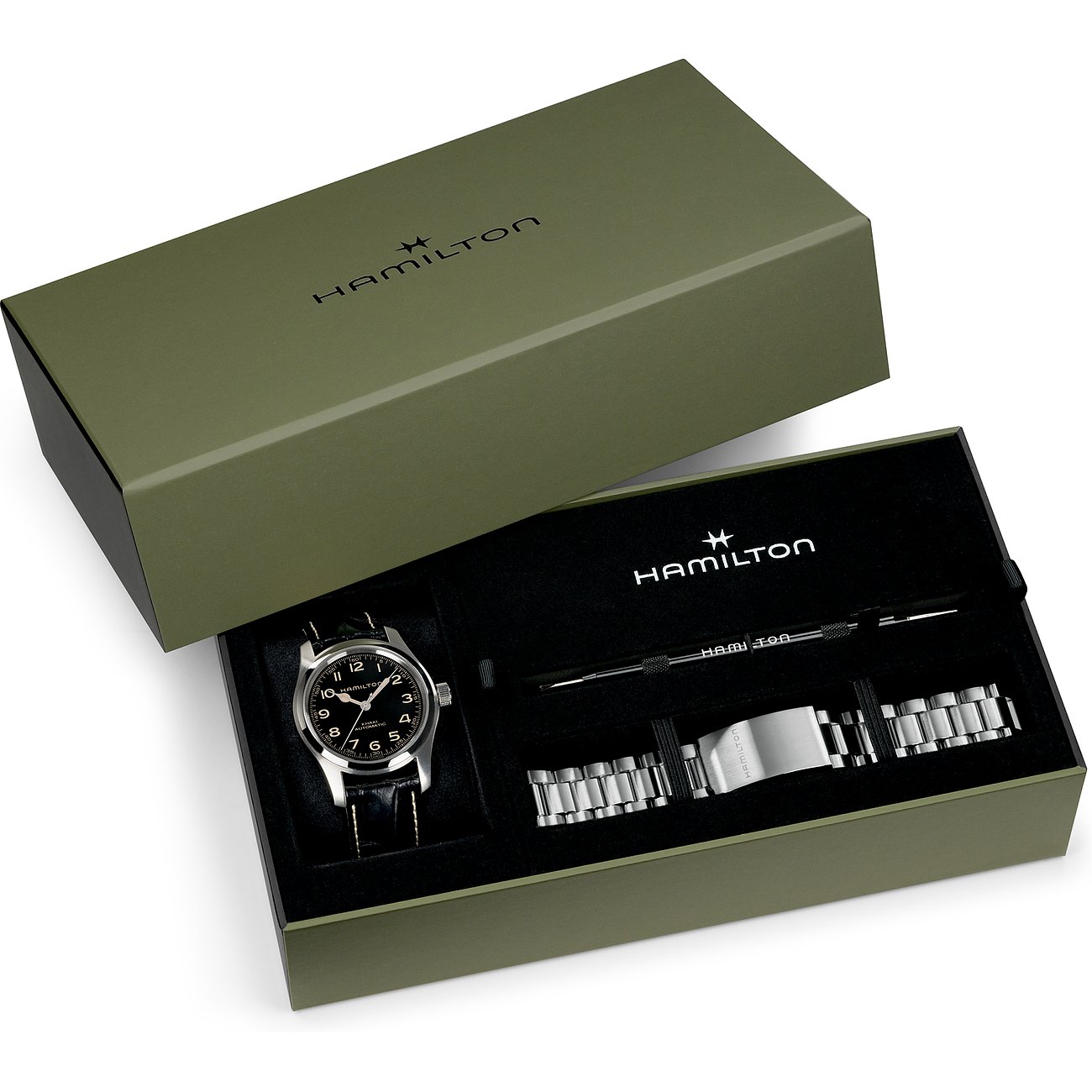 Die Hamilton Armbanduhr aus Edelstahl liegt in einer geöffneten, olivgrünen Box neben einem silbernen Wechselarmband.